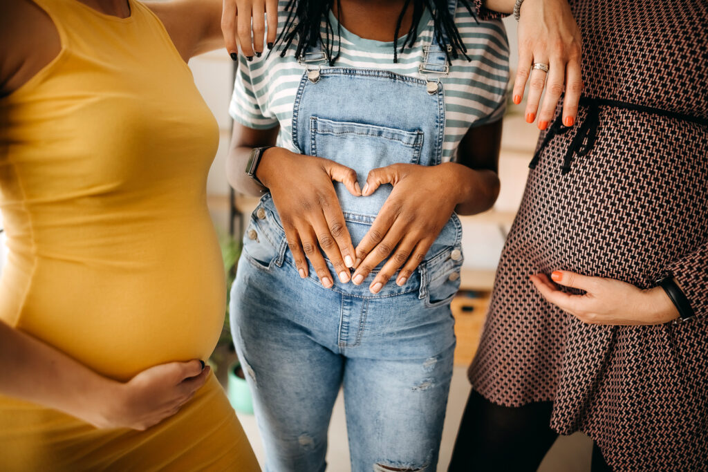 three women holding their pregnant bellies.