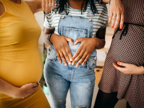 three women holding their pregnant bellies.