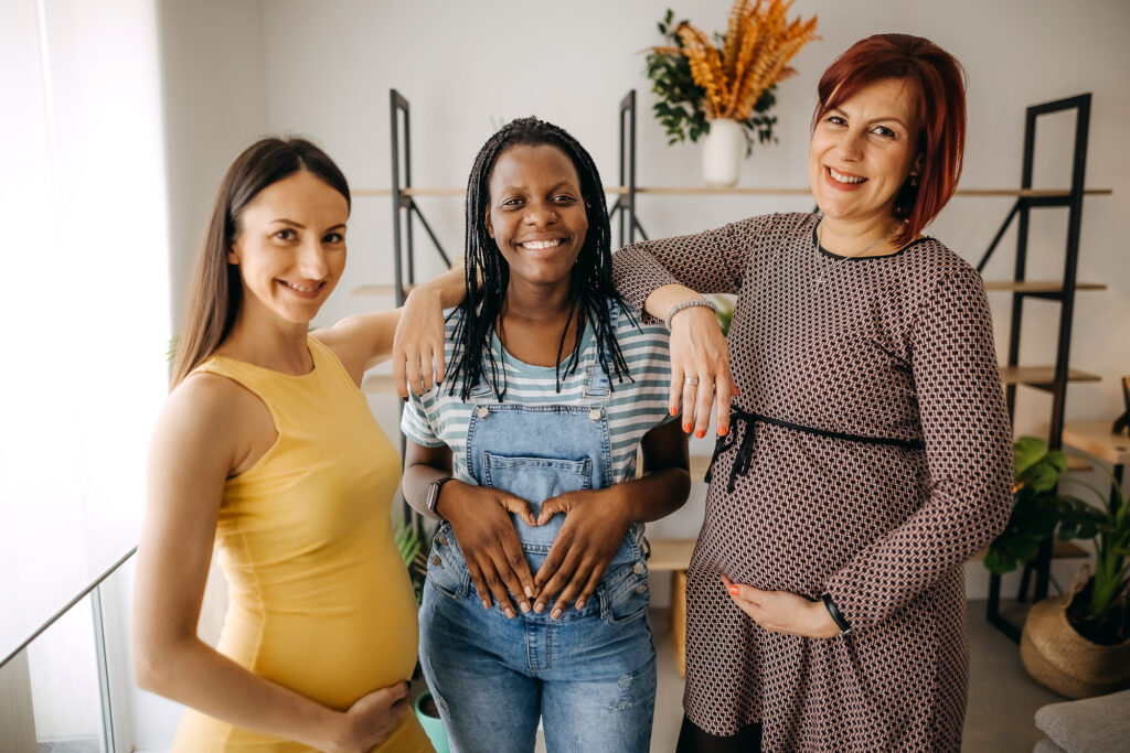 three women holding their pregnant bellies.