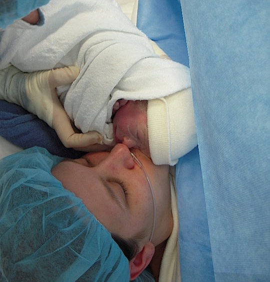mom giving newborn baby a kiss