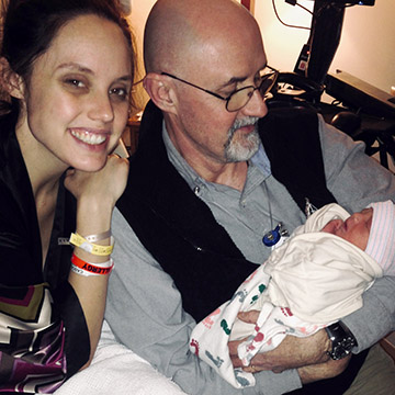 newborn being held by family with smiling woman and man