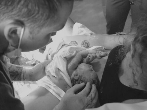 Black and white image of mom and dad holding newborn baby