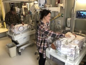 Color image of Marley and Reigny's parents caring for them in S,t. Luke's specialized care nursery.