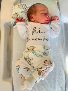 Radley in baby crib with a white onesie and floral pants