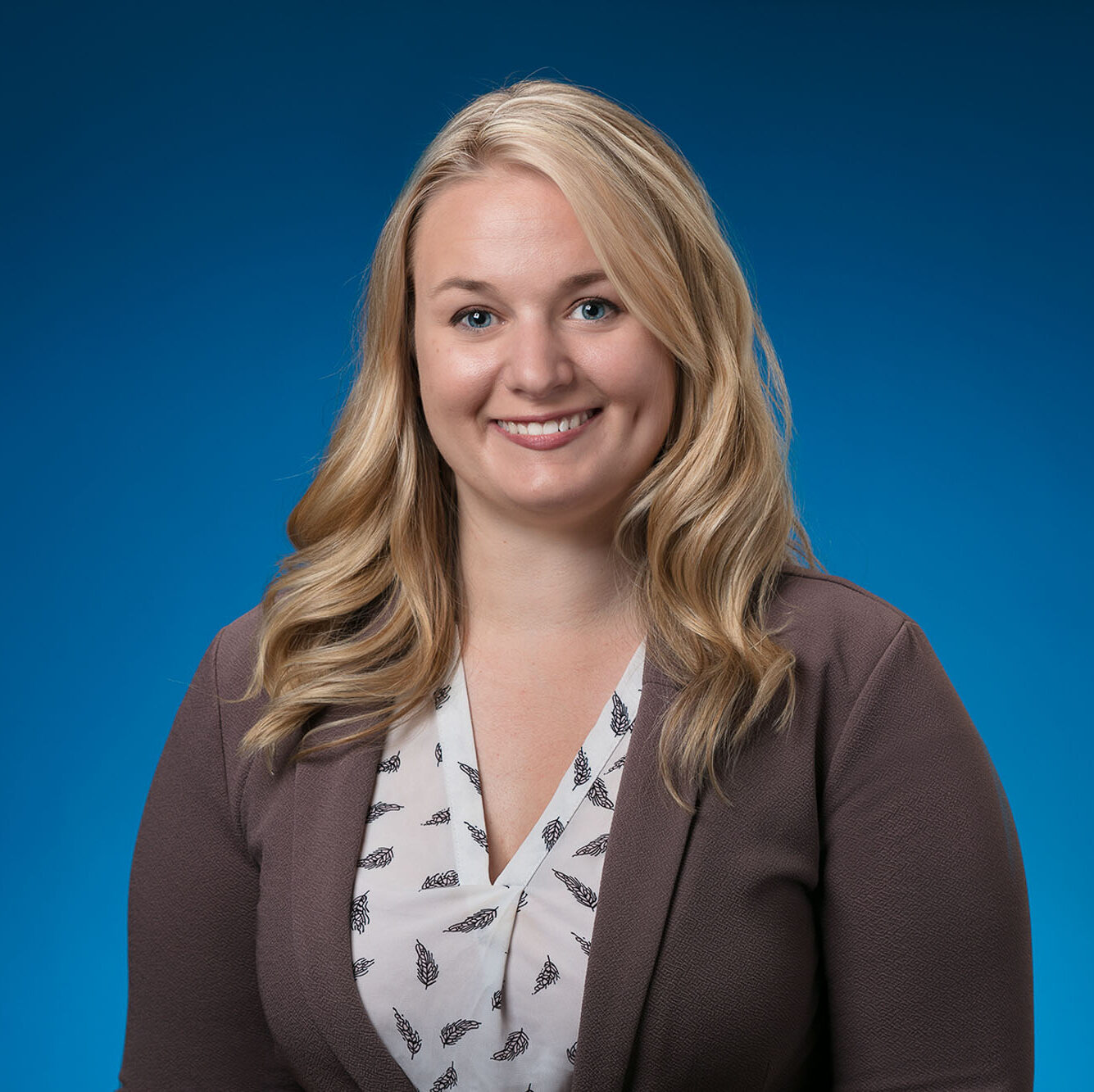Tianna Hughes, APRN, CNP is smiling in front of a bright blue background.