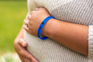 Pregnant woman holding her belly while wearing the blue band.