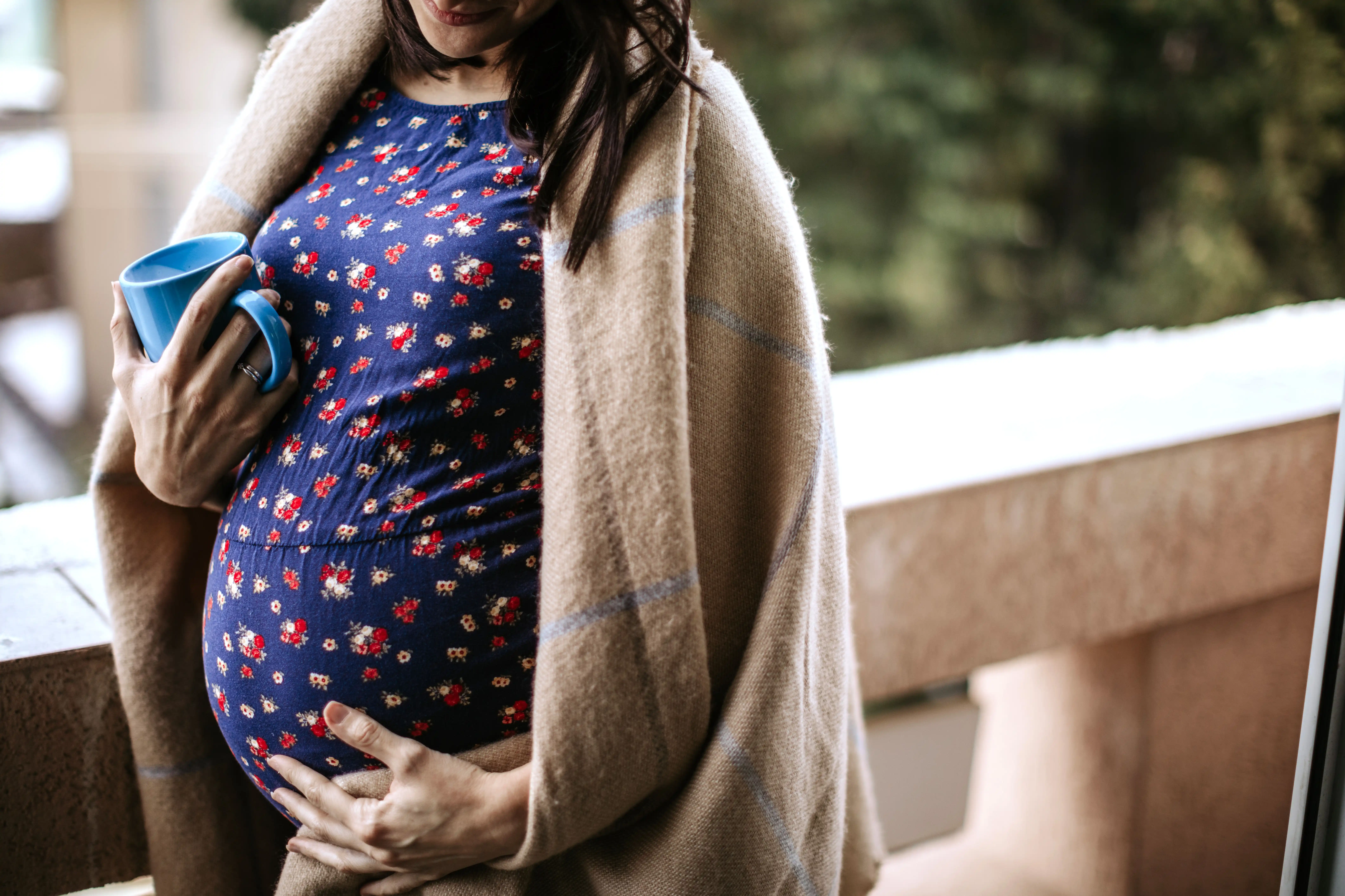 Pregnant woman holding her belly outside.
